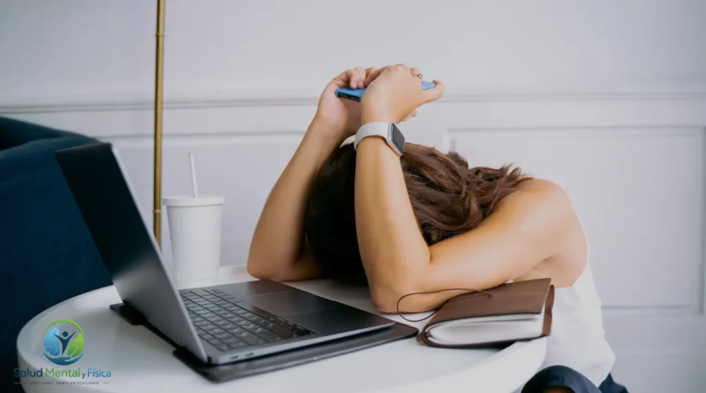 Mujer acostada en el escritorio con el celular en las manos.